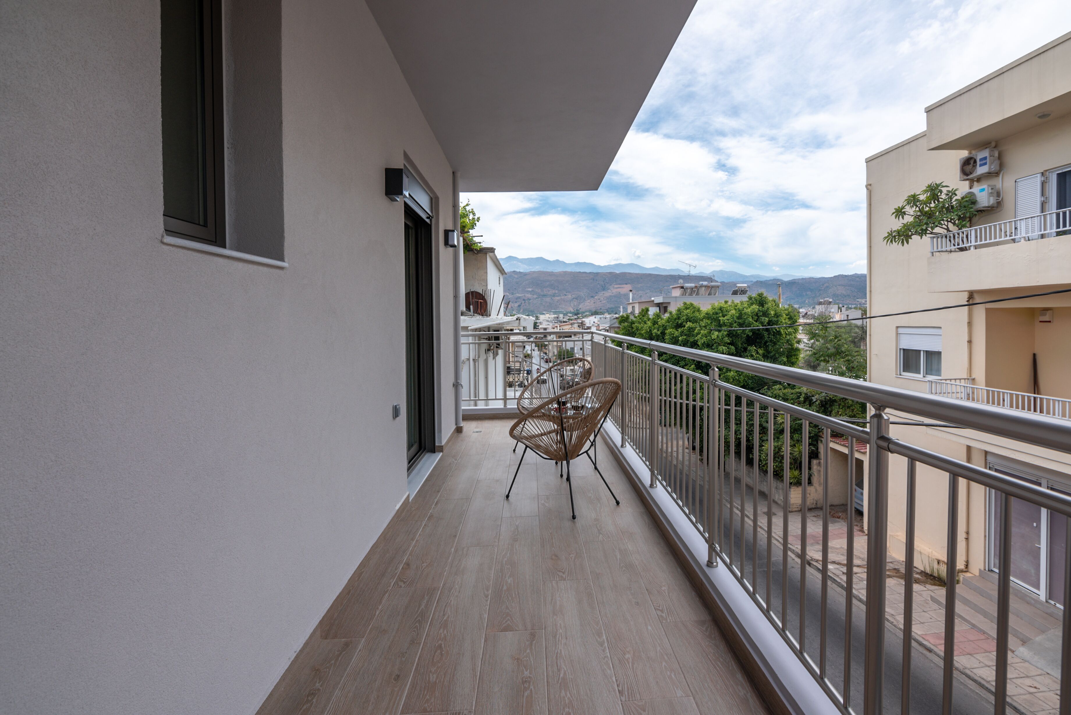 A balcony with a wooden floor, a chair, and a railing.