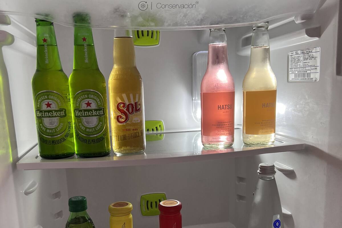 Un refrigerador repleto de diversas bebidas, incluyendo Heineken, Sol, Hatsu y HATSU.