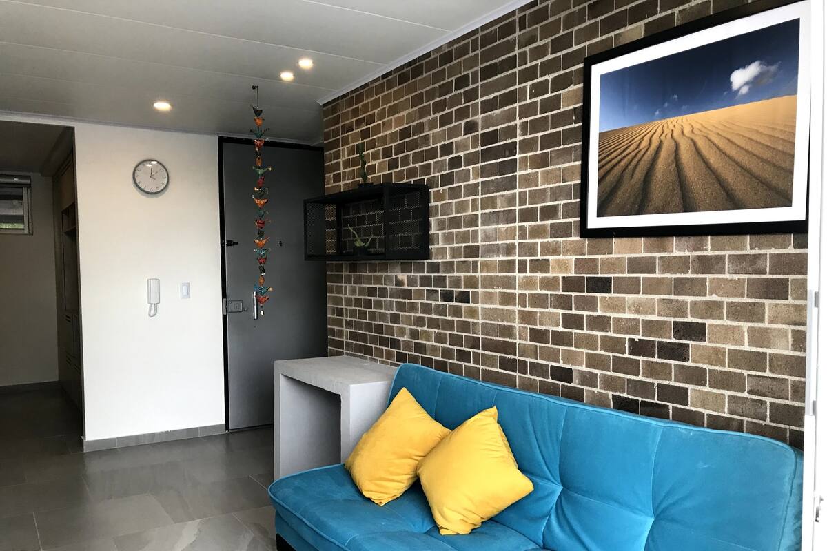 Una habitación con un sofá azul, un reloj, un adorno colgante y un cuadro en la pared.