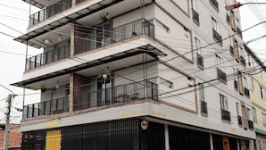 Un immeuble à plusieurs étages doté de balcons, d’une entrée sécurisée et de lignes électriques apparentes.