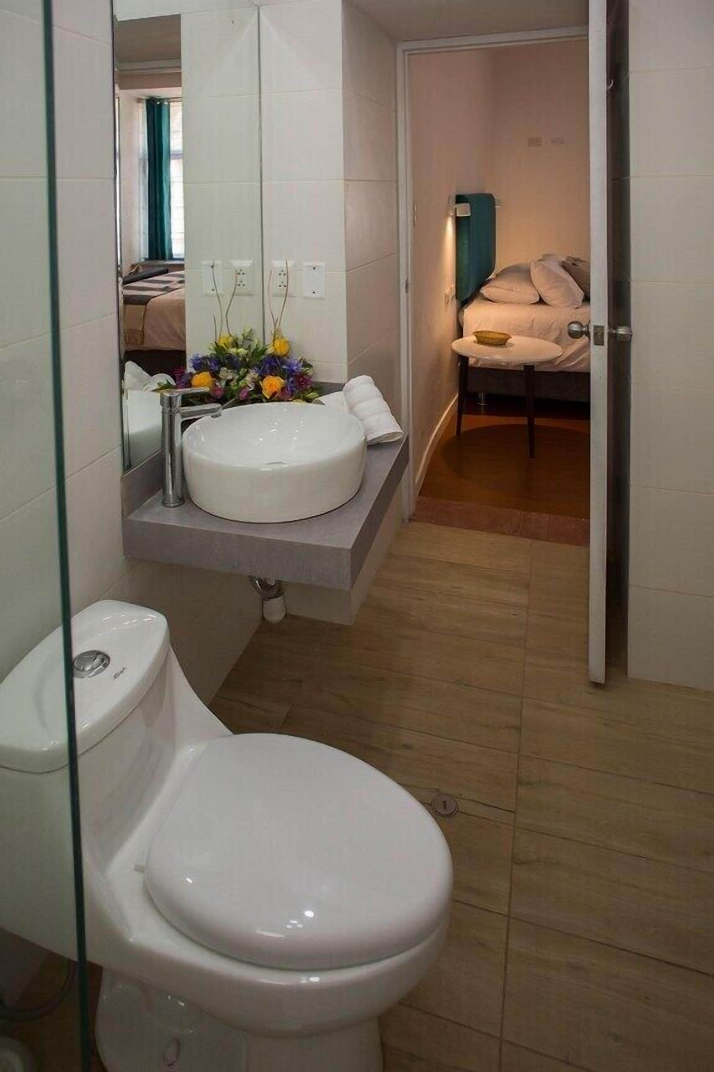 A compact bathroom with a white toilet, a white sink, and a mirror above the sink.