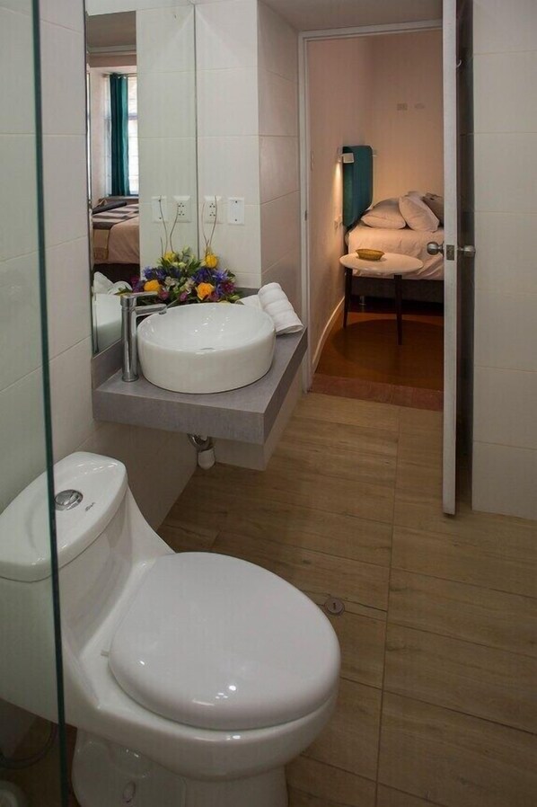 Une petite salle de bain avec des toilettes blanches, un lavabo blanc et un miroir au-dessus du lavabo.