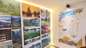 A wall with a series of scenic photographs and a detailed bus service information poster. - Hanowood Homestay & Travel (Hanoi)