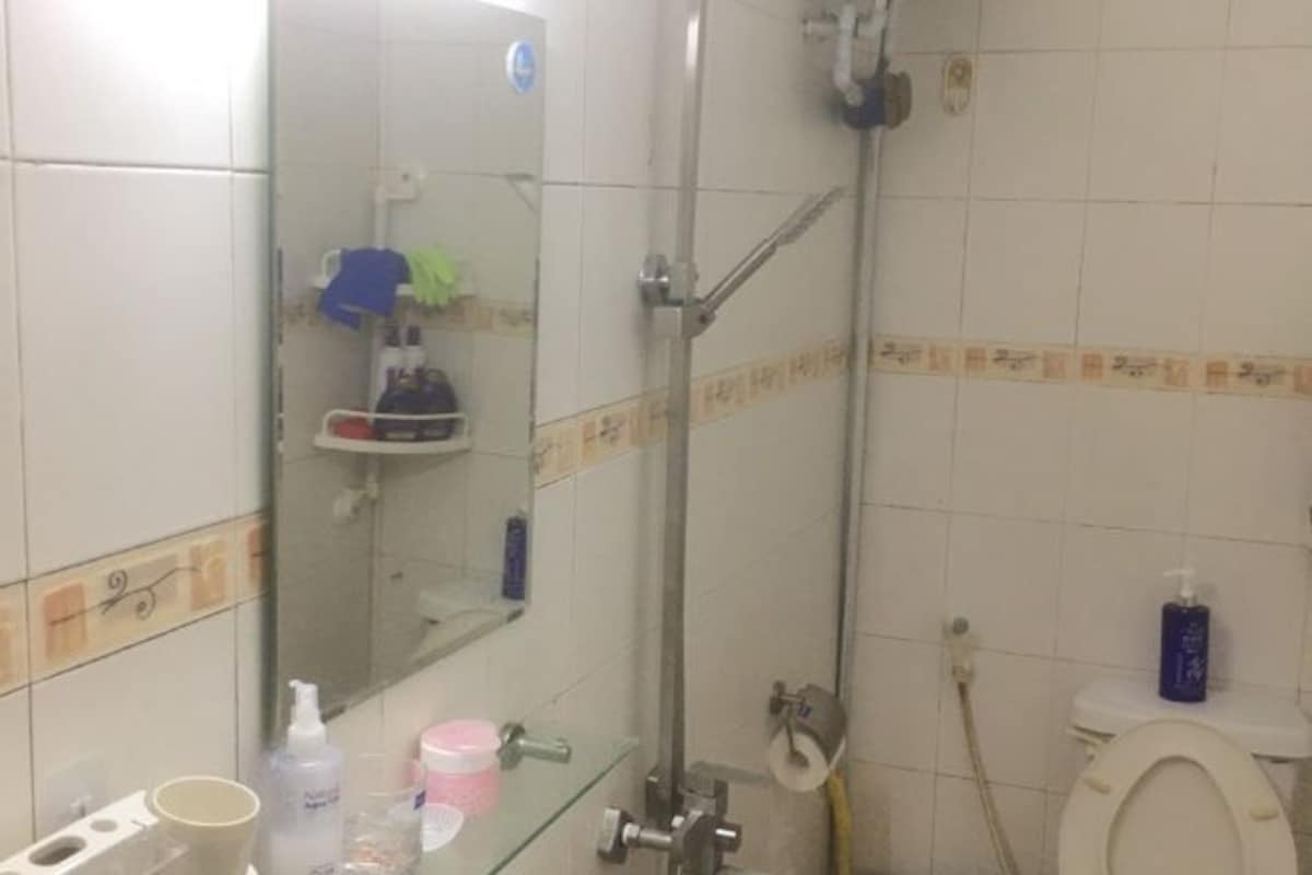 A bathroom with a glass shower enclosure, a toilet, and a sink with toiletries.