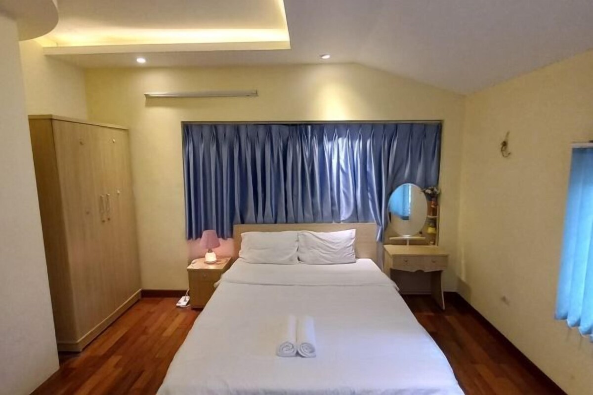A neatly arranged hotel room with a bed, a wardrobe, a bedside table with a lamp, and a mirror.