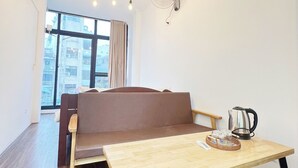 A modern living room with a brown sofa, a wooden table with a kettle and a basket, and a ceiling fan. - Hanowood Homestay & Travel (Hanoi)
