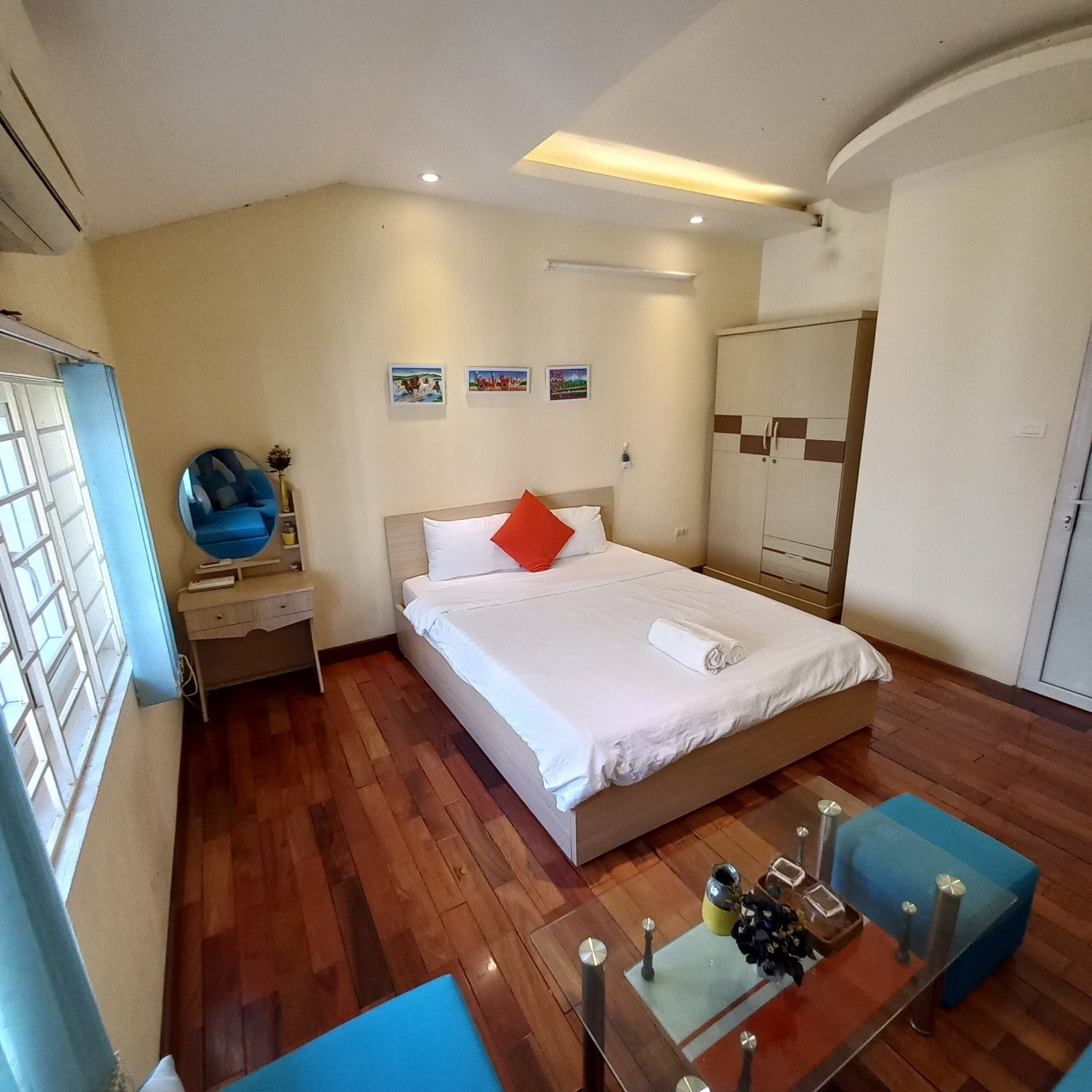 Una habitación de hotel con cama, escritorio, silla, armario y espejo.