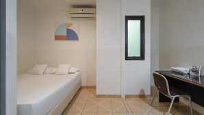 A small, clean room with a bed, a desk, and a window. - Cove Horizone (Bandung)