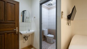 A bathroom with a wooden door, a sink, a mirror, and a toilet. - Cove Horizone (Bandung)