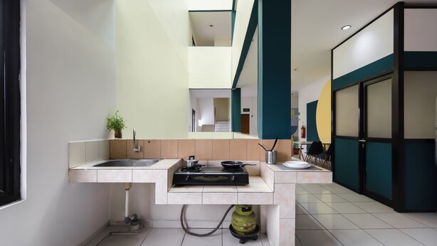 A modern kitchen with a built-in sink, stove, and a green gas cylinder. - Cove Horizone (Bandung)