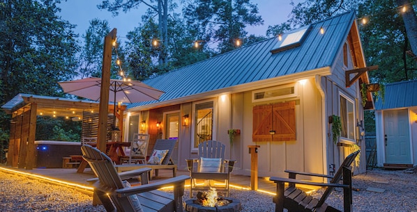 Une cabane en bois avec une véranda, un espace salon extérieur et un foyer.