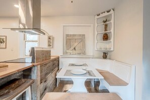 Una cocina compacta con encimera de madera, armarios blancos y una zona de asientos integrada con banco.