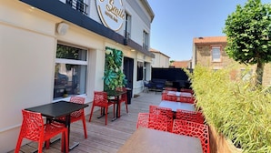 Un bar de hotel llamado "Le Smile" con mesas al aire libre y una terraza de madera.