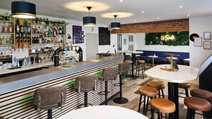 Una zona de bar con mostrador, taburetes y una sala de estar con mesas y sillas.
