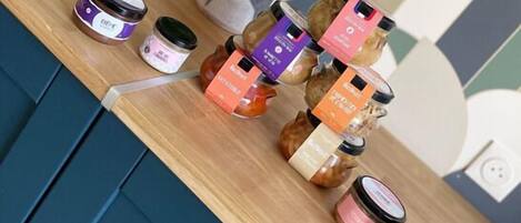 A wooden shelf with various jars of products, a potted plant, and a patterned wall in the background.