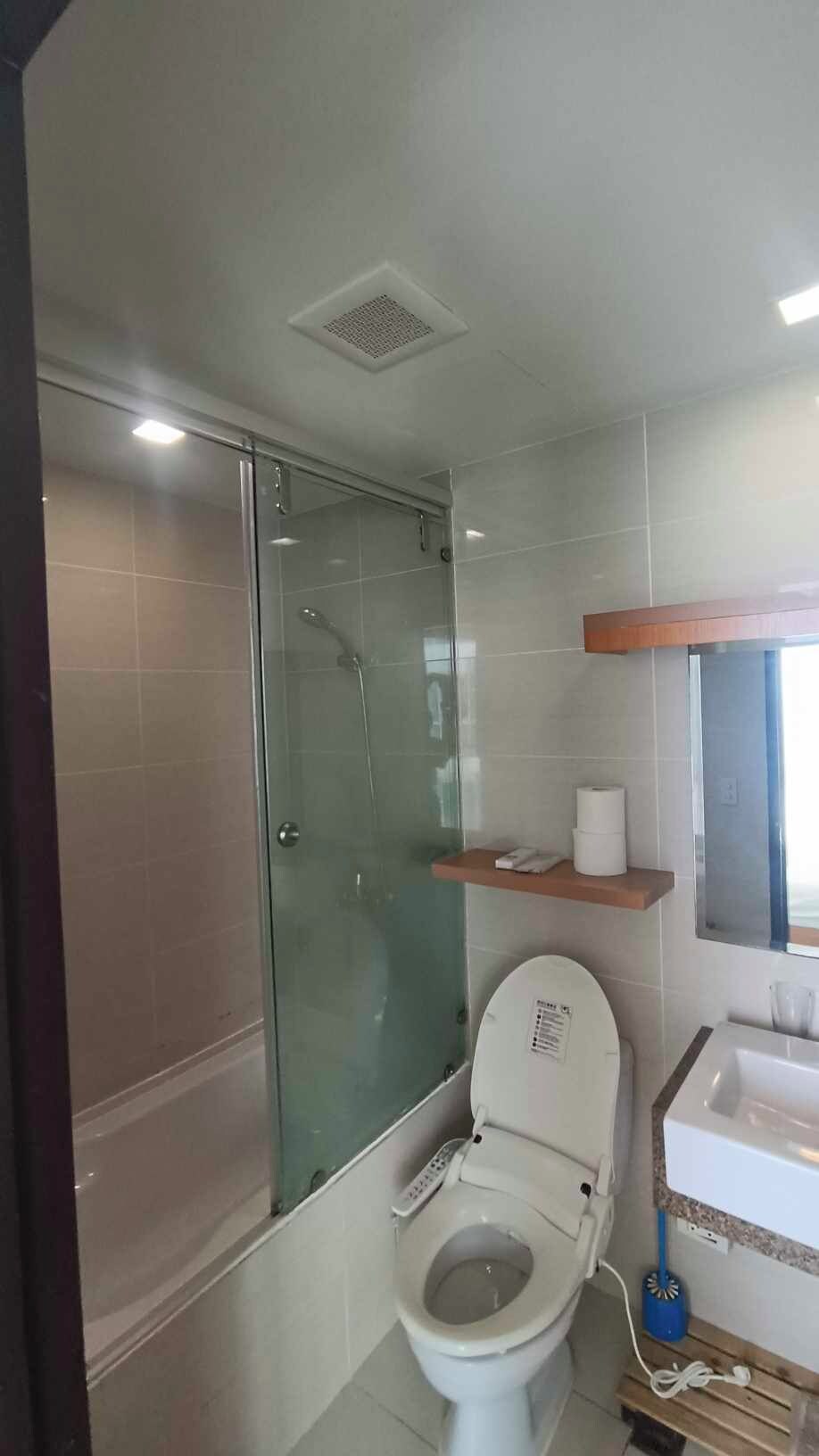 A bathroom with a glass-enclosed shower, a toilet, and a sink.