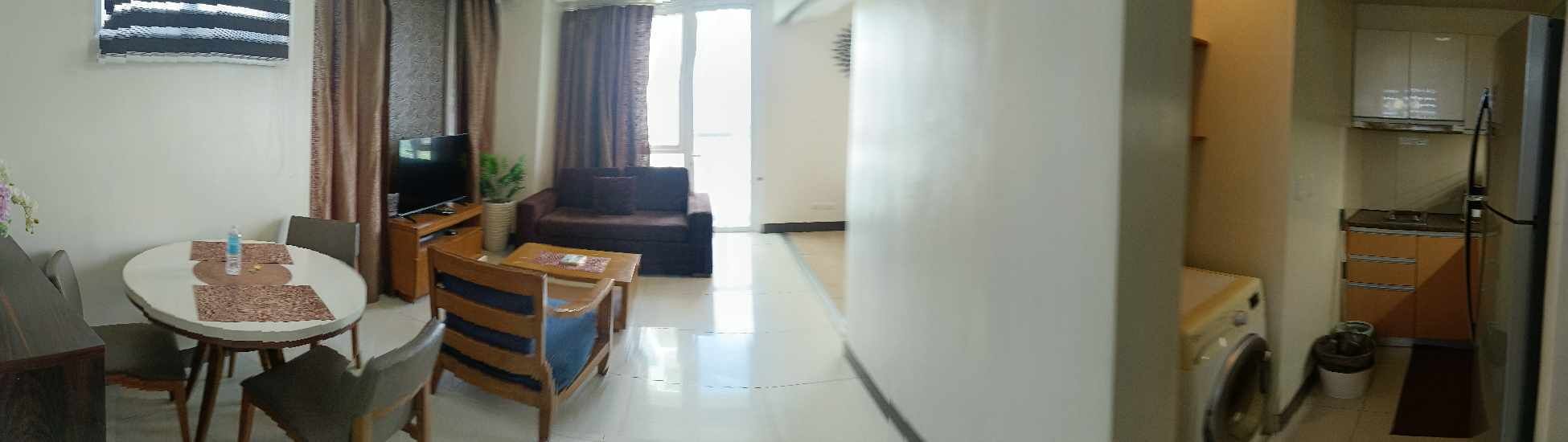A compact living space with a dining area, a sofa, a TV, and a kitchen area.