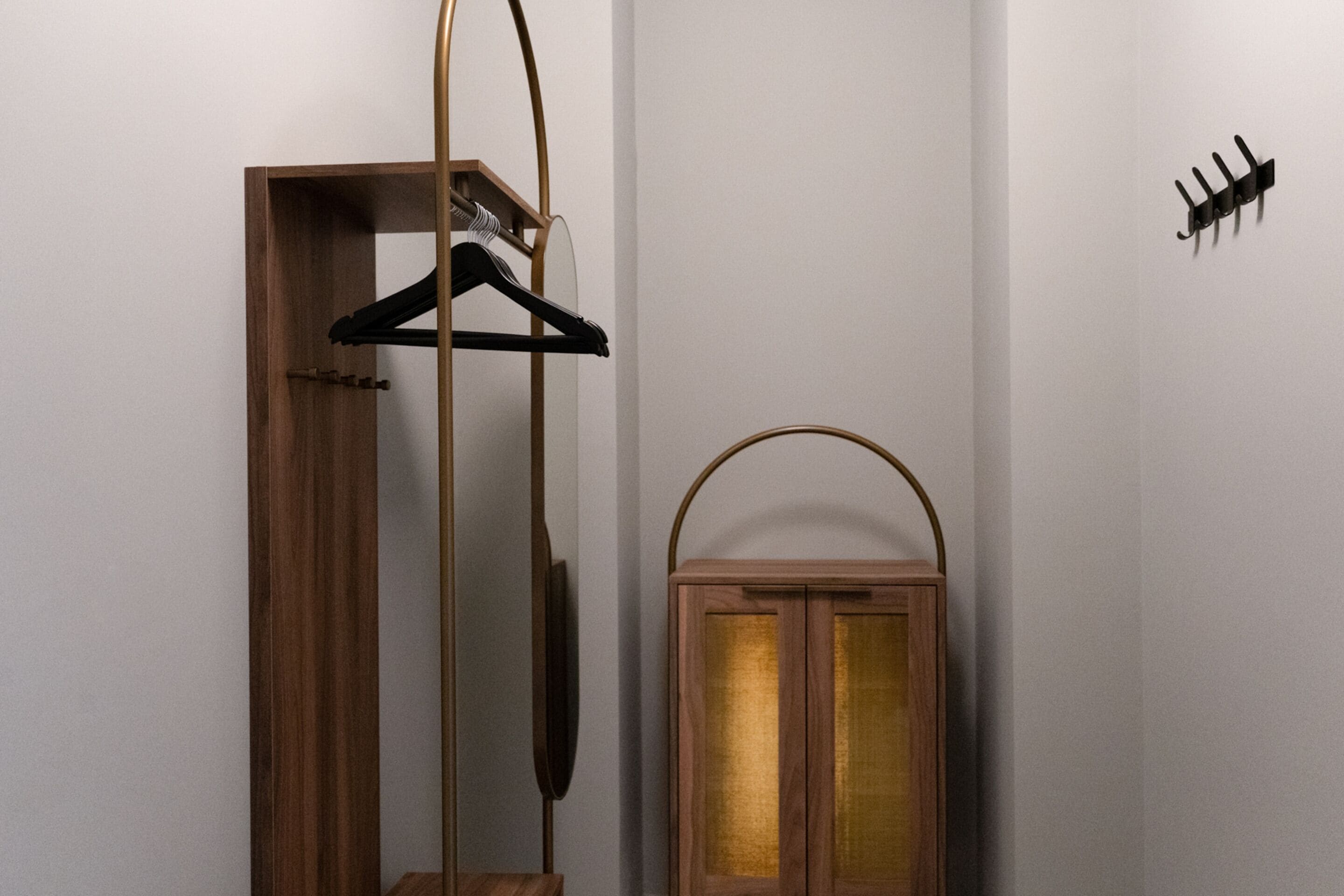 A wooden wardrobe with a hanging rack, a mirror, and a small cabinet with glass doors.