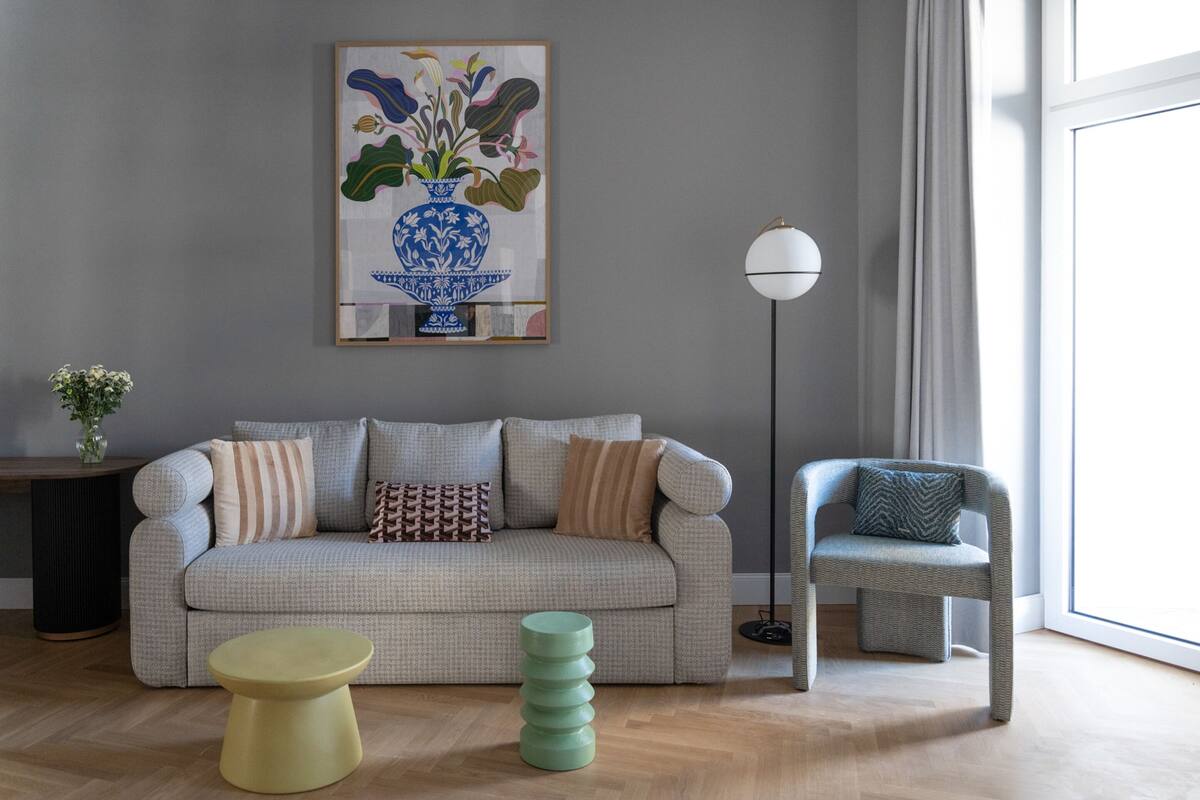 Ein Wohnzimmer mit einer Couch, einem Sessel, einem runden Tisch und einer Stehlampe.