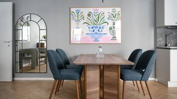 Ein Essbereich mit einem Holztisch, zwei blauen Stühlen und einem floralen Bild in einem Rahmen an der Wand.