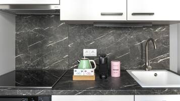 Une cuisine moderne avec un dosseret en marbre noir, un évier en acier inoxydable et une machine à café.