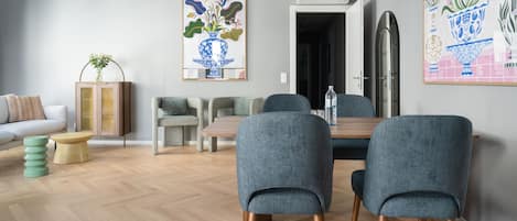 Una sala de estar moderna con comedor, con piso de madera, sillas tapizadas grises, una mesa de comedor de madera y un sofá.