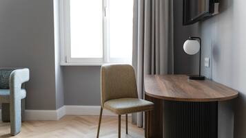 A modern room with a wooden dining table, a grey upholstered chair, and a television mounted on the wall.
