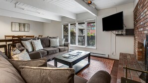 A modern living room with a sectional sofa, a coffee table, and a TV mounted on the wall.