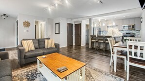 A modern living room with a sofa, coffee table, and dining area.