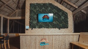 Un área de recepción con pared de bambú, una pantalla de televisión y un banco de madera.