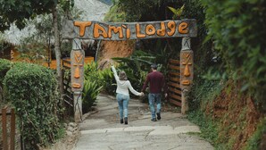 Un sendero que lleva a un letrero de madera con el nombre 'Tami Lodge'.