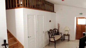 A room with a wooden staircase, a white door, a chair, a small table, and a lamp.