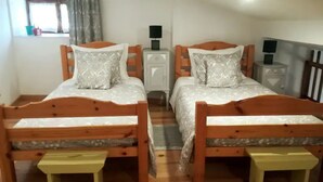A room with two wooden beds, each with a matching nightstand and lamp.