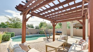 Un patio extérieur couvert, doté d’une piscine, de meubles en bois et d’une structure en forme de pergola.