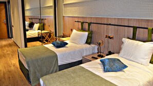 Une chambre d’hôtel avec deux lits, un miroir, une tête de lit en bois et une petite table avec une chaise.