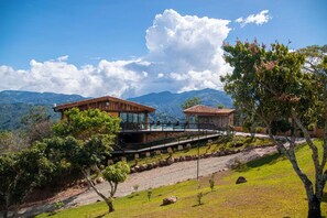 A two-story house with a pool, surrounded by lush greenery and mountains in the background. - Hotel Pico Colorado (Rosario)