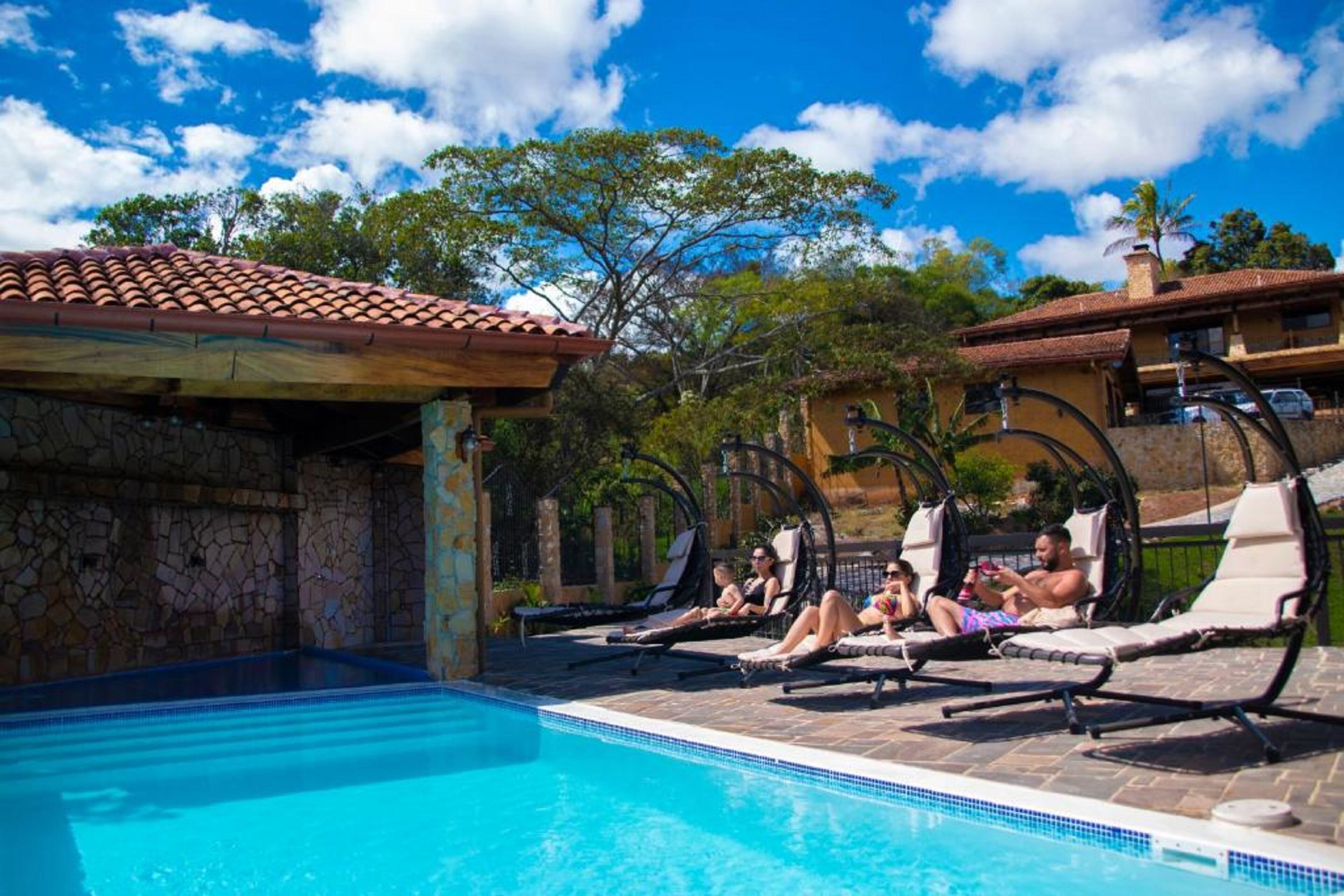 A swimming pool with lounge chairs and a stone wall.