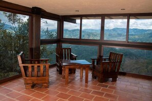 A room with a large window offering a mountain view, wooden furniture, and a tiled floor. - Hotel Pico Colorado (Rosario)