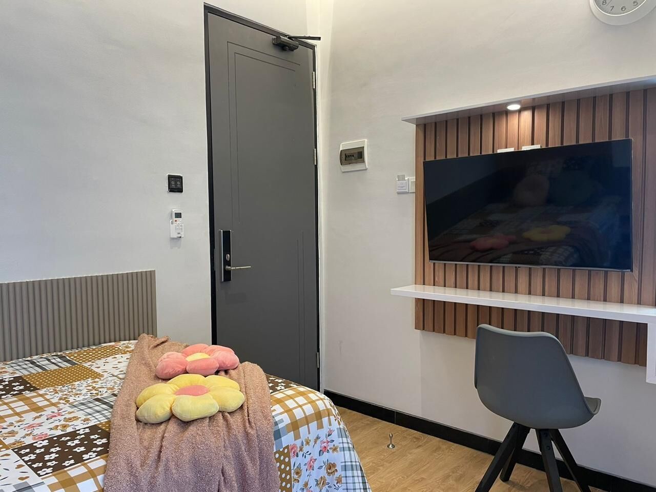 A room with a bed, a TV mounted on the wall, a chair, and a door.