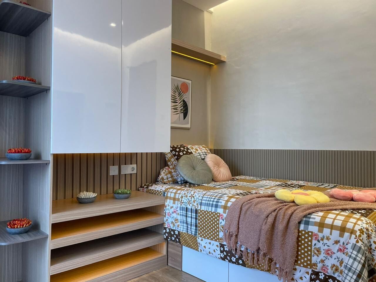 Un dormitorio con cama, estanterías y una lámpara fijada a la pared.