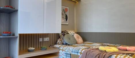Un dormitorio con cama, estanterías y una lámpara fijada a la pared.
