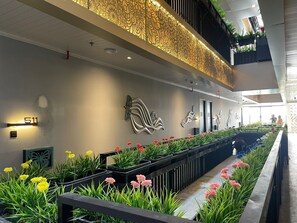 Un intérieur moderne avec un long comptoir d’accueil, des œuvres d’art décoratives murales et une variété de plantes en pot.