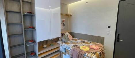 A bedroom with a bed, a wardrobe, and built-in shelves.