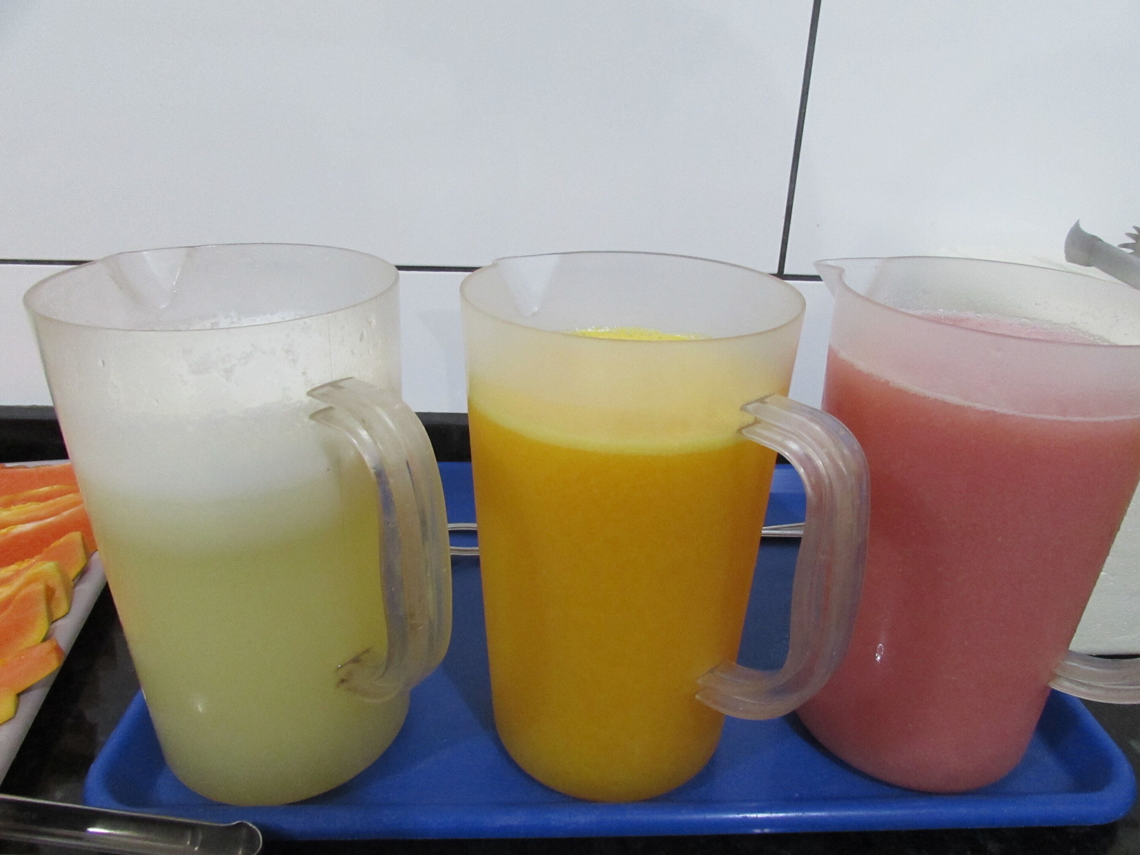 Drie kannen met kleurrijke drankjes op een blauwe schaal.