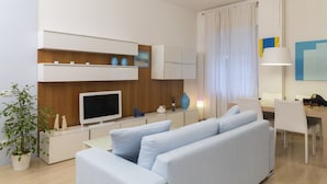 Un salon moderne avec un canapé, un téléviseur et un coin repas.