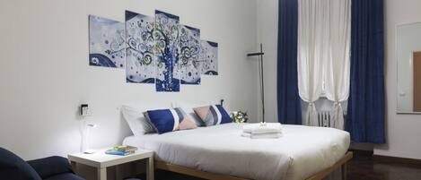 A modern bedroom with a bed, bedside table, and artwork on the wall.