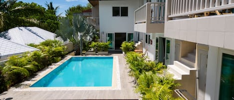 Un bâtiment moderne doté d’une piscine, d’un espace extérieur aménagé et d’une végétation luxuriante.