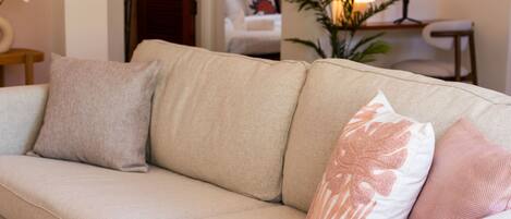 A beige sofa with three cushions in a living room.