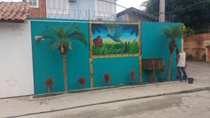 A mural on a wall with palm trees and a bird. - Kandui Flats Maresias (São Sebastião)