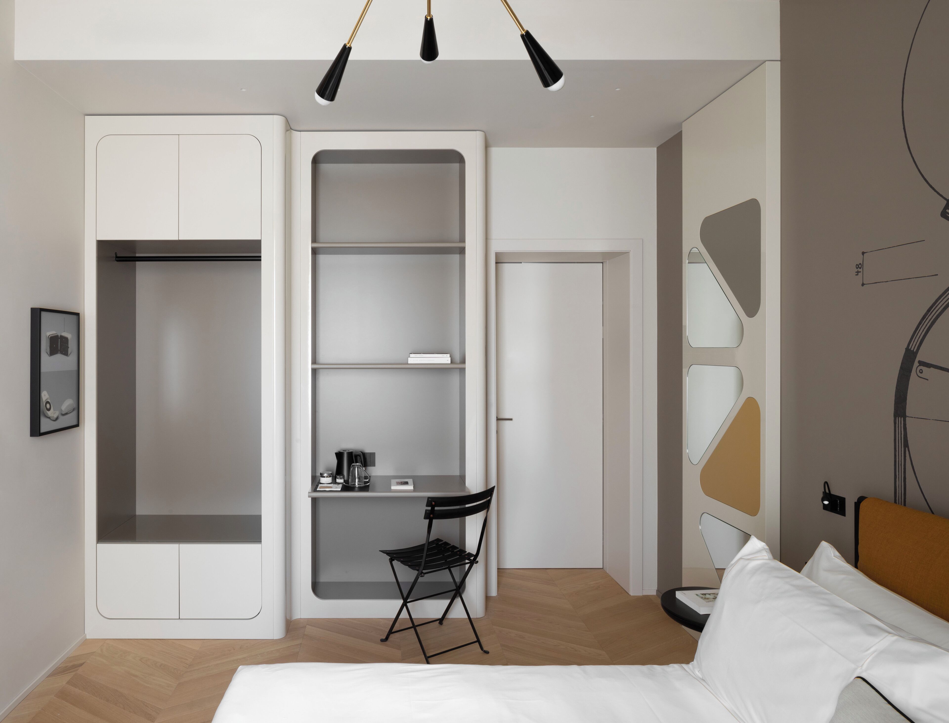 Een moderne hotelkamer met een bed, een bureau met stoel, een kledingkast en een inbouwkast.
